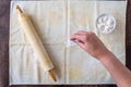 WomanÃ¢â¬â¢s hand dropping flour on pastry cloth, wood rolling pin with cloth cover, small bowl of flour